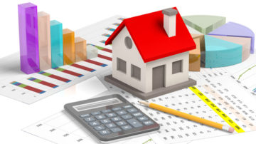 Model house with red roof on table with calculator and pencil