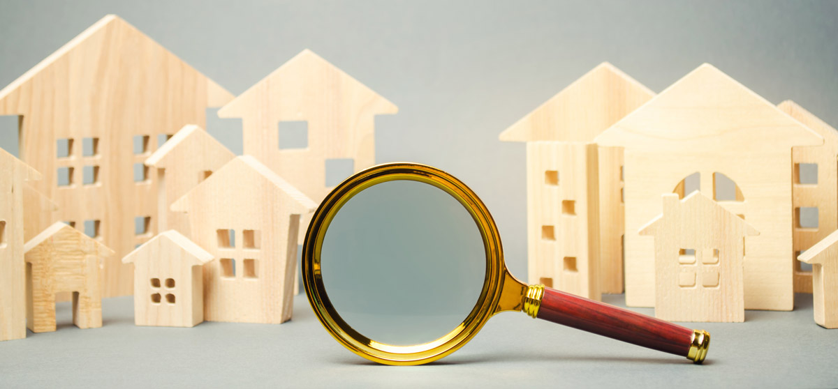 Cut out wood houses stacked in back of magnifying glass